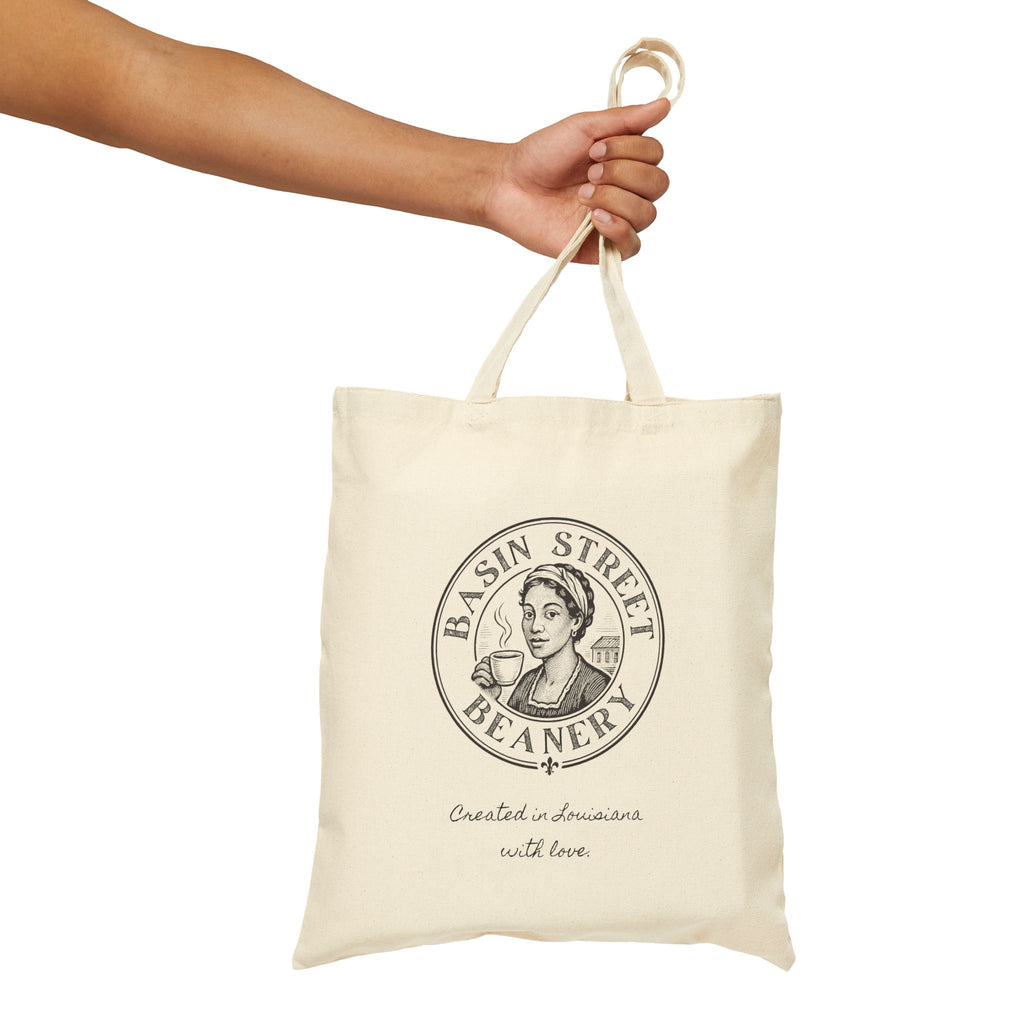 Tote bag with 'Basin Street Beanery' logo held by a hand on a white background